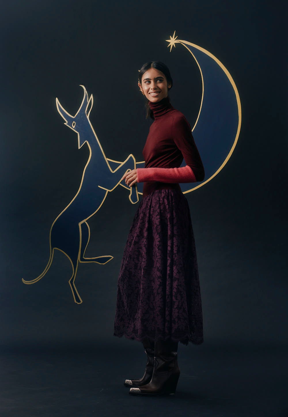 Model wearing a slim turtleneck sweater with elongated cuffs, styled with skirt, editorial setting